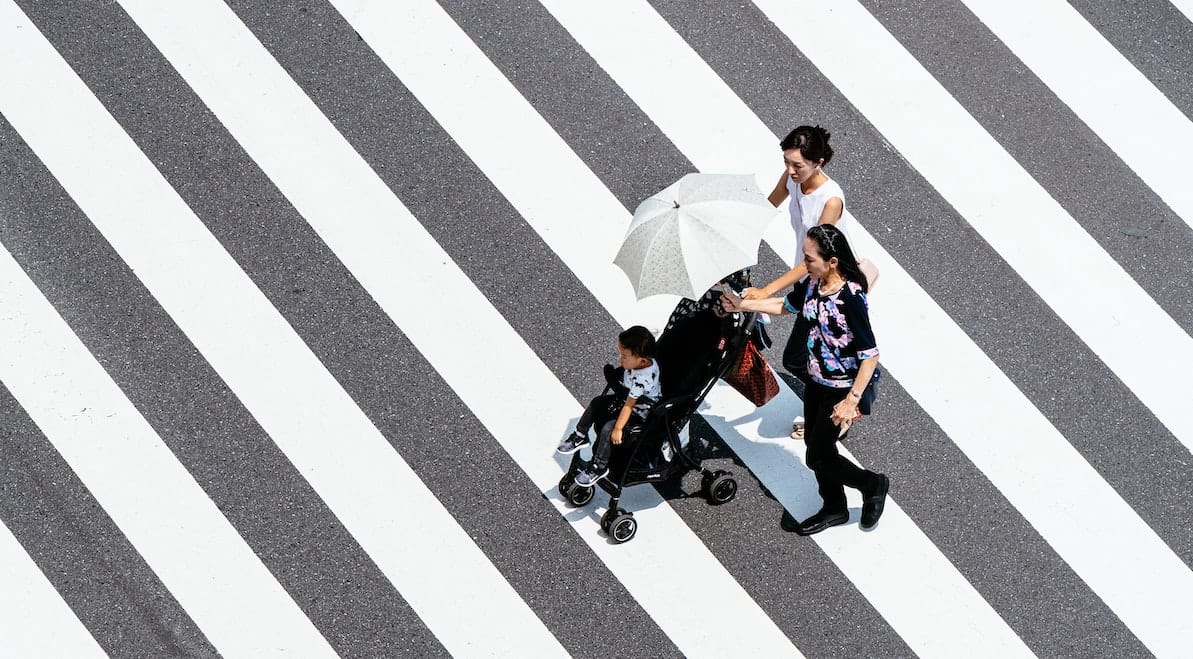 aerial view of a family walking across black and white diagonal lines on the ground