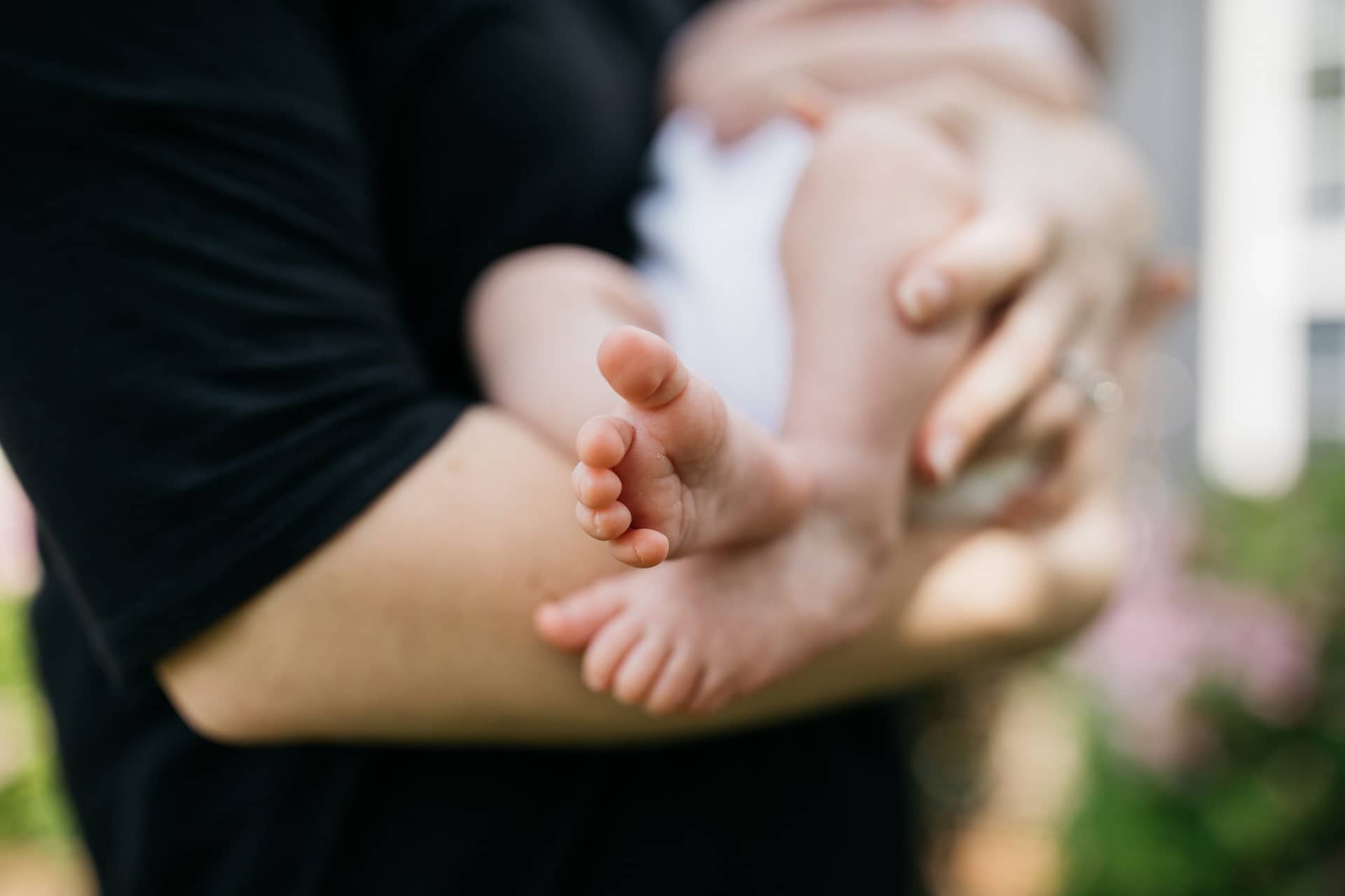 a mother holds a baby in her arms baby's feet in foreground as she breastfeeds