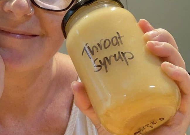 woman holds jar of homemade throat syrup