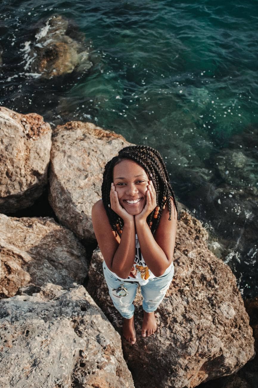 happy black tourist on boulder near sea